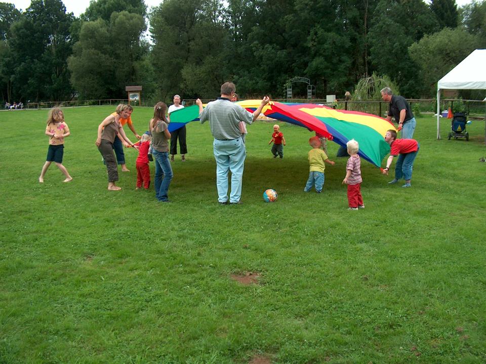 Kinder und Eltern im gemeinsamen Spiel auf der Wiese neben dem Grillplatz